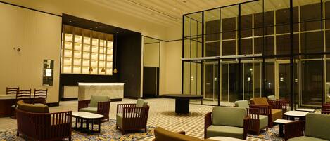 A spacious lobby with multiple seating areas, a large glass wall, and a patterned carpet.