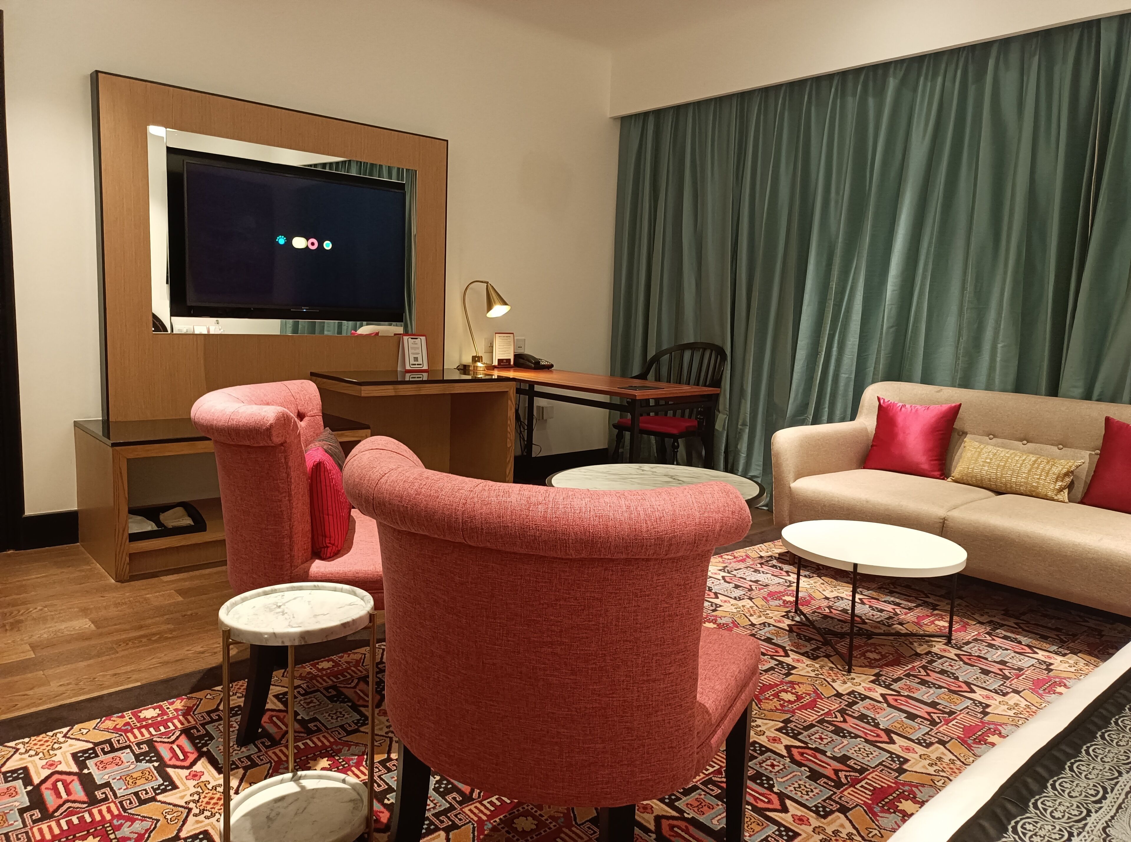 A modern living room with a television, a sofa, a desk, and a patterned rug.