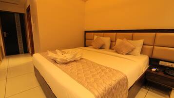 Una habitación de hotel con una cama grande, una mesita de noche con teléfono y una puerta con detalles decorativos.