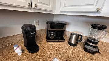 Una cocina equipada con cafetera, licuadora, hervidor y dispensador de cápsulas Keurig.