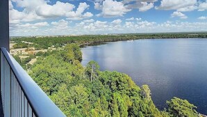 Une vue sur un lac, avec une rive bordée d’une forêt et un ciel dégagé.