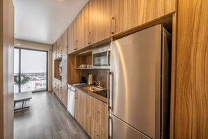 A modern kitchen with wooden cabinets, a stainless steel refrigerator, and a microwave. - Canyon Haus 309 (Park City)