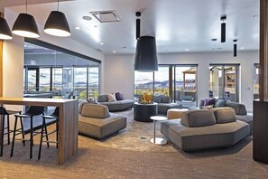 A modern interior with a bar area, sofas, and a view of mountains. - Canyon Haus 309 (Park City)