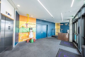 A hotel lobby with a colorful mural, a reception desk, and an elevator.