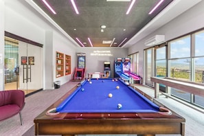 A pool table with a blue felt surface, surrounded by arcade machines and a red sofa. - Save on Your Last Minute 4th of July Getaway! (Park City)