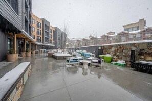 An outdoor patio area with seating and planters, surrounded by buildings.