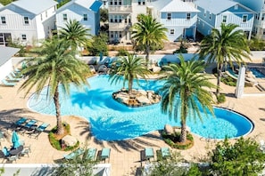 A resort with a central swimming pool surrounded by palm trees and lounge chairs.
