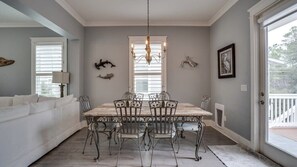 A dining area with a wooden table and metal chairs, a chandelier, and decorative wall art.