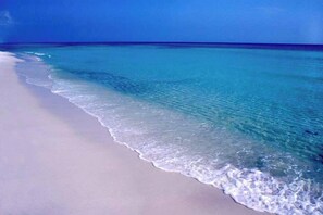 Une plage à l’eau turquoise et limpide et au sable blanc.