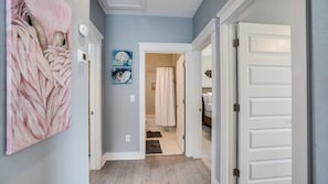 A hallway with a door leading to a bathroom, a light switch, and a wall-mounted light fixture.