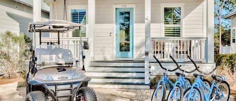 A house with a porch, a golf cart, and a bicycle rack.