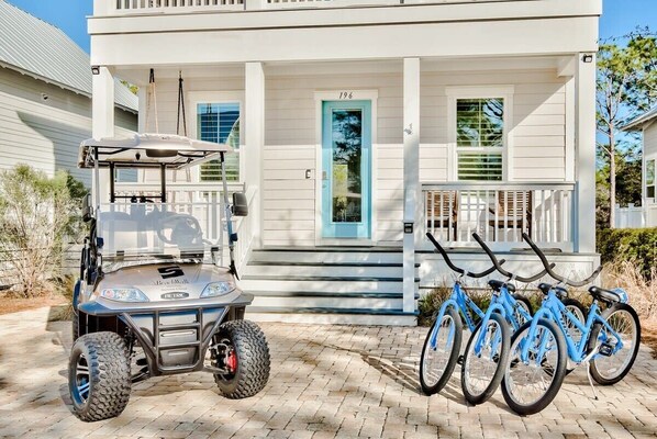 A house with a porch, a golf cart, and a bicycle rack.