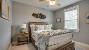A bedroom with a bed, nightstands, a ceiling fan, and a window with blinds.