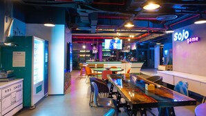 Zona de bar moderna con letreros de neón, asientos y una pantalla de televisión.