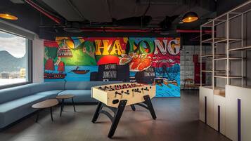 A room with a foosball table, a sofa, and a mural depicting a cityscape and food.
