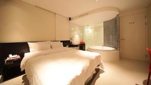 Una habitación de hotel moderna con una cama grande, un baño separado con bañera y una silla roja.
