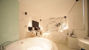 Un baño moderno con una bañera grande, zona de ducha, tocador con espejo y cama con ropa de cama blanca.