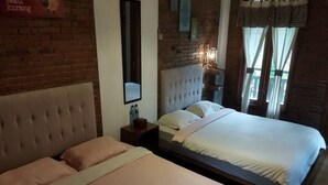Een tweepersoonskamer met twee bedden, een bakstenen muur, een spiegel en een nachtkastje met een lamp.