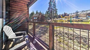 Une terrasse en bois avec une chaise, une vue sur un quartier résidentiel avec des maisons et des arbres, et un ciel dégagé.
