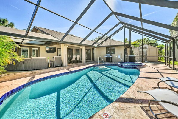 A covered outdoor swimming pool with a patio area, lounge chairs, and a barbecue grill. - Port Charlotte Retreat w/ Heated Pool & Spa! (Port Charlotte)