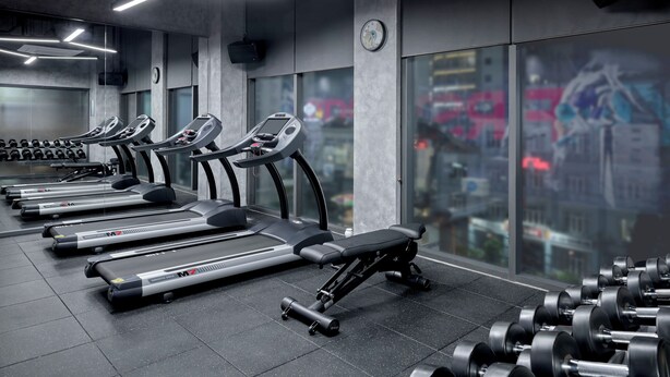 Un gimnasio con cintas de correr, pesas y un banco.
