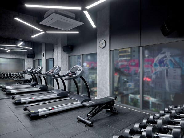 Une salle de sport équipée de tapis de course, d’haltères et d’un banc de musculation.