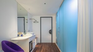 Un baño moderno con un lavamanos blanco, un espejo y una silla morada.