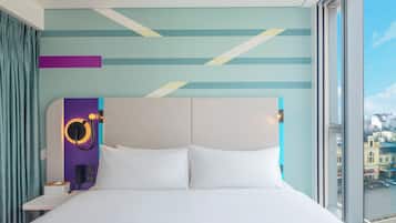 Ein modernes Hotelzimmer mit einem großen Bett, einem Kopfteil mit einer runden Beleuchtung und Blick auf die Stadt durch das Fenster.