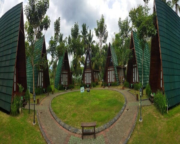 A circular courtyard with a central bench, surrounded by traditional-style buildings with green roofs and wooden walls. - Borobudur Balkondes Saka Pitu (Yogyakarta)