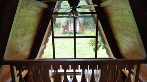 A room with a sloped ceiling, a window with a view of a garden, and a ceiling fan. - Borobudur Balkondes Saka Pitu (Yogyakarta)