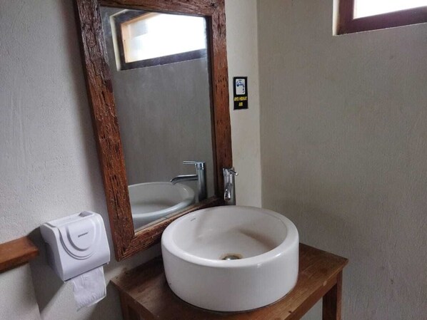 A bathroom with a wooden vanity, a white sink, a mirror, and a hand dryer. - Borobudur Balkondes Saka Pitu (Yogyakarta)