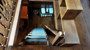 A wooden staircase leading to a room with a bed and a shelf with folded towels. - Borobudur Balkondes Saka Pitu (Yogyakarta)