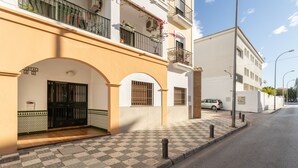 A building with a checkered pavement, a black gate, and a car parked on the street.