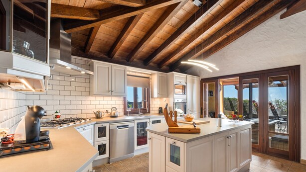 A modern kitchen with white cabinetry, a large island, a gas stove, and a view through the glass door to the outside. - Pet-friendly Villa Finca Toledo with Pool, Terrace, Garden, A/C & Wi-Fi (San Miguel de Abona)
