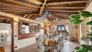 A dining area with a wooden table, chairs, and a kitchen in the background. - Pet-friendly Villa Finca Toledo with Pool, Terrace, Garden, A/C & Wi-Fi (San Miguel de Abona)