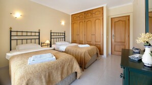 A room with two beds, wooden wardrobe, and a dresser with a vase. - Holiday Home "Primavera" with Sea View, Pool, Wi-Fi, A/C, Terraces & Garden (Carvoeiro)