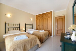 A room with two beds, wooden wardrobe, and a dresser with a vase. - Holiday Home "Primavera" with Sea View, Pool, Wi-Fi, A/C, Terraces & Garden (Carvoeiro)