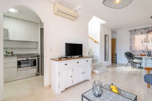 Una cocina moderna con armarios blancos, horno empotrado y televisor de pantalla plana sobre una encimera de madera.