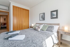 Une chambre à coucher avec un grand lit, une armoire en bois, deux tables de chevet avec des lampes et deux tableaux encadrés accrochés au mur.
