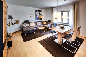 Un salon moderne avec un canapé, une table à manger, des chaises et une grande fenêtre.