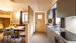 Una cocina compacta con puerta de madera, una zona de comedor con banco y un banco empotrado con mesa.
