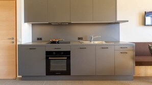 Une cuisine compacte dotée d’un four encastré, d’une plaque de cuisson et d’un évier.