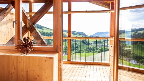 Un intérieur en bois agrémenté de grandes fenêtres donnant sur des collines verdoyantes.