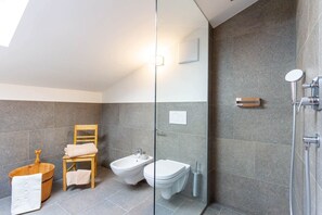 Une salle de bain moderne équipée d’un bidet, de toilettes et d’une chaise en bois.