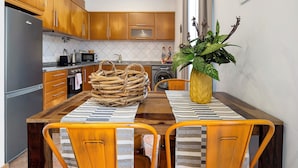 Una cocina con armarios de madera, un refrigerador de acero inoxidable, un microondas y una mesa de comedor con sillas.