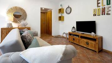 Ein Wohnzimmer mit Sofa, Fernseher, Holzschrank, Wanddekoration und einer Tür zu einem anderen Raum.