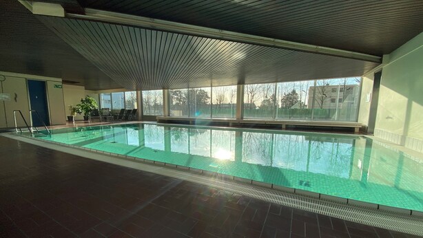 An indoor swimming pool with a tiled floor and a ceiling with a ribbed design. - Skyline apartment with pool 2-6 guests with Netflix (Kronberg im Taunus)