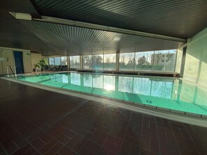 An indoor swimming pool with a tiled floor and a ceiling with a ribbed design.