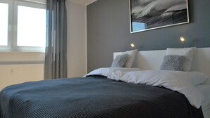 A bedroom with a large bed, a window with curtains, and a painting on the wall. - Skyline apartment with pool 2-6 guests with Netflix (Kronberg im Taunus)