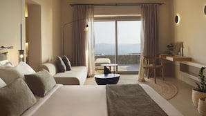 A modern hotel room with a large bed, a desk, a chair, and a view of the sea. - Collini Hotel Mykonos, WorldHotels Elite (Mykonos)